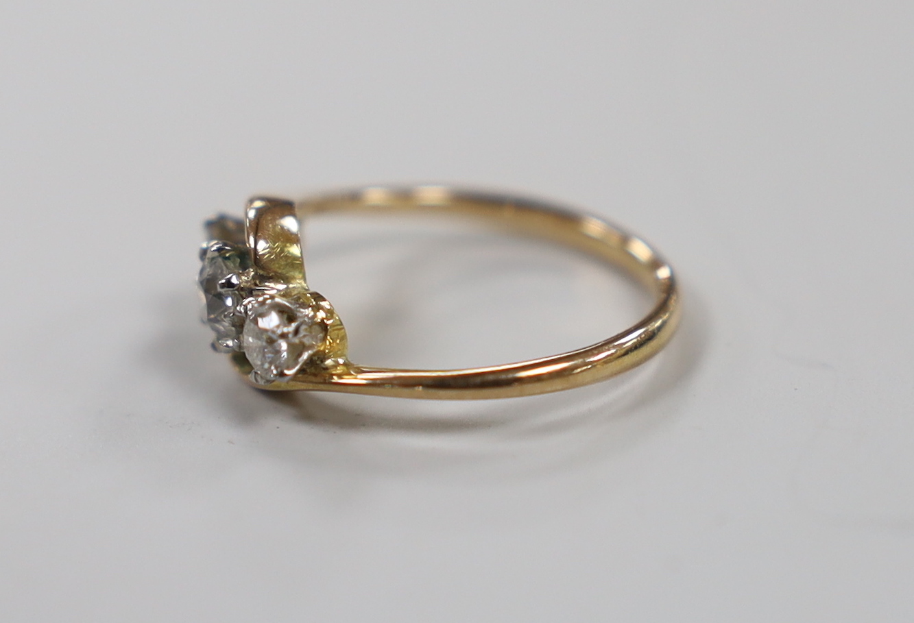 A 14k and three stone diamond set crossover ring, size H, gross weight 2 grams.